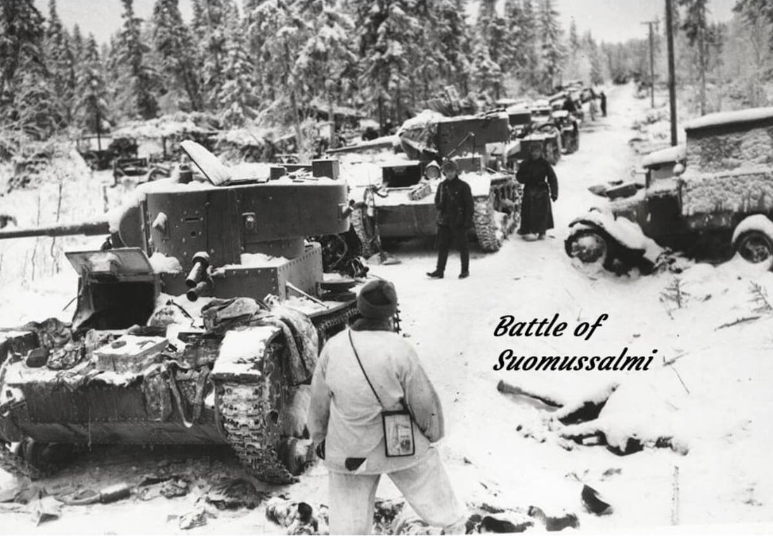 Snow-covered forest road filled with destroyed and abandoned Soviet T‑26 and BT‑5 tanks, with Finnish soldiers standing among the wreckage during the Battle of Suomussalmi in the Winter War.