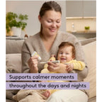 A woman sitting on a couch with a baby in a yellow outfit, holding a thermometer and a small tube. A text overlay reads: 'Supports calmer moments throughout the days and nights'.