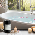 ila Apothecary product next to a bathtub with floating flower petals, candles and stones, creating a calming spa‑like atmosphere.