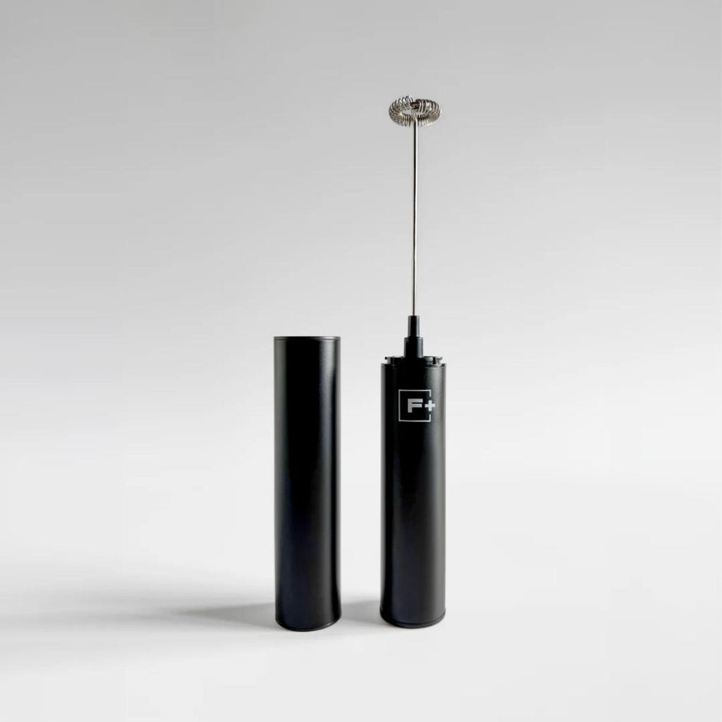 A sleek black electric frother with a metal whisker attachment standing upright next to its matching black cylindrical container, set against a clean light gray studio background.