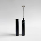 A sleek black electric frother with a metal whisker attachment standing upright next to its matching black cylindrical container, set against a clean light gray studio background.