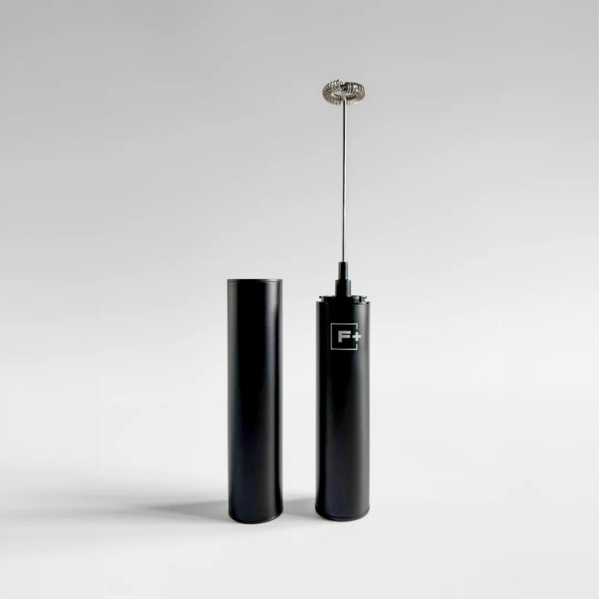 A sleek black electric frother with a metal whisker attachment standing upright next to its matching black cylindrical container, set against a clean light gray studio background.