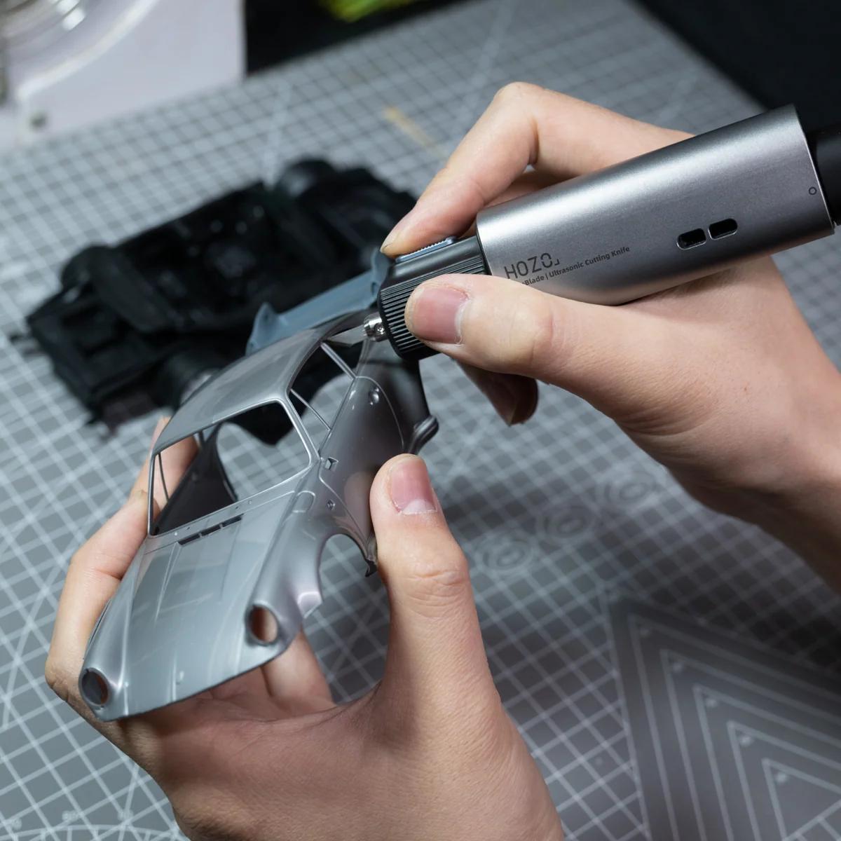 Person using a Hozz tool on a metal object with a gray cutting mat in the background