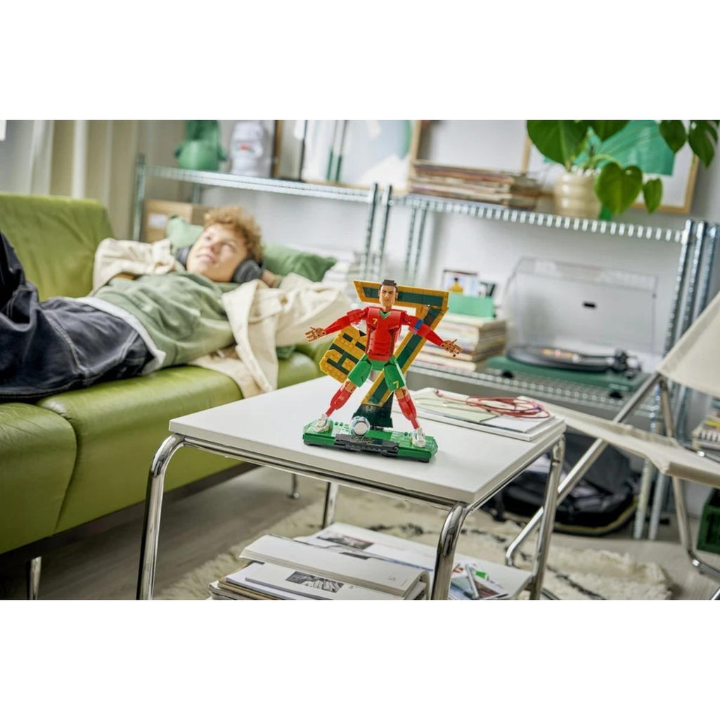Living room with a person lying on a couch and a superhero figurine on a table.