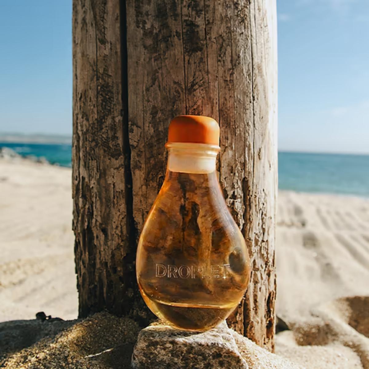 Bottle shaped like a light bulb on a beach with ocean view
